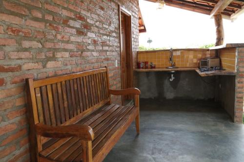 a wooden bench sitting next to a brick wall at Chale com vista e acesso ao Rio Grande - MG in Delfinópolis