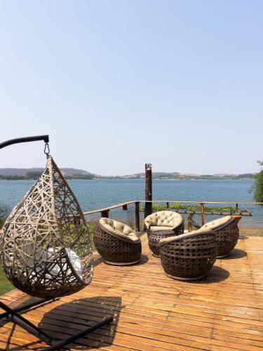 a wooden deck with a group of chairs and a swing at Chale com vista e acesso ao Rio Grande - MG in Delfinópolis
