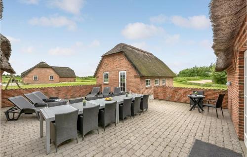 a patio with a long table and chairs and a building at 7 Bedroom Gorgeous Home In Ulfborg in Øby