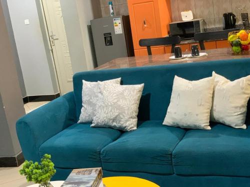 a blue couch with three white pillows on it at Kisaasi Serene-1bedroom in Kampala