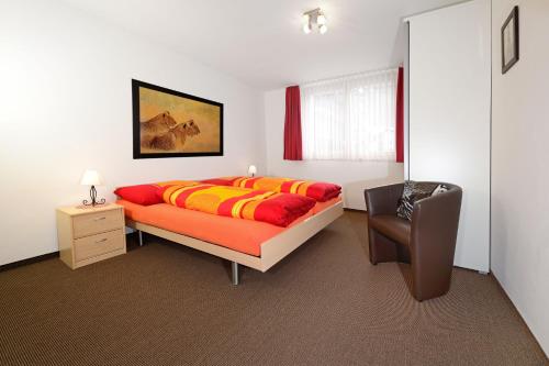 ein Schlafzimmer mit einem Bett und einem Stuhl in der Unterkunft Ferienwohnung Haus Achilles in Zermatt