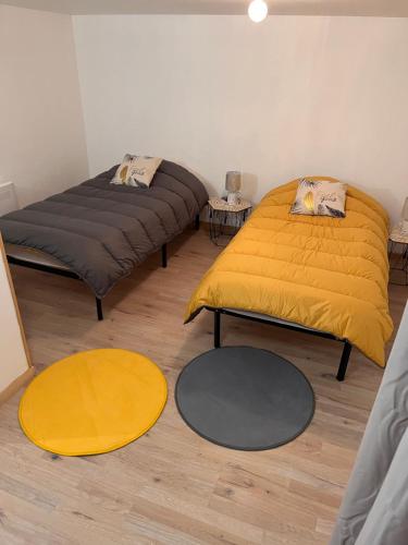 2 lits dans une chambre avec des draps jaunes et 2 tapis dans l'établissement Duplex La Bourboule, à La Bourboule
