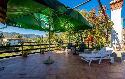 a patio with a bench and a green umbrella at Holiday Home In Vele Mune in Vele Mune