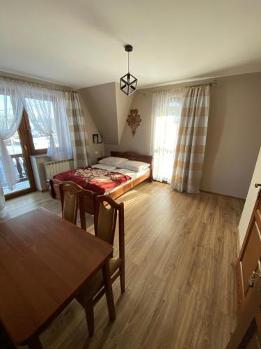 a living room with a table and a bed at Domek pod lasem in Białka Tatrzanska