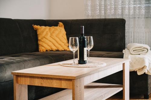 a bottle of wine and two wine glasses on a coffee table at Apartman Valerija in Doboj