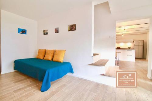 Cette chambre blanche dispose d'un lit avec une couverture bleue. dans l'établissement Villa L'olivier, à La Seyne-sur-Mer