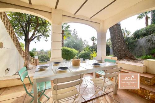 une table et des chaises blanches sur une terrasse avec un arbre dans l'établissement Villa L'olivier, à La Seyne-sur-Mer