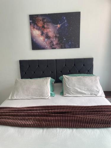 a bed with a black headboard and a painting on the wall at Casa Estelar in Cabo Frio