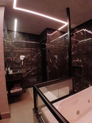 a bathroom with a tub and a black wall at Motel Marselha 5 in Sao Paulo
