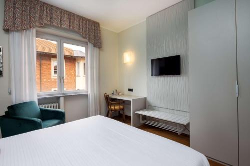 a hotel room with a bed and a chair and a window at Best Western Hotel Crimea in Turin