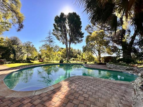 a swimming pool in a park with trees at Farm stay at Thyme Cottage on Haldon Estate in Bloemfontein