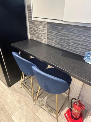 a table with two blue chairs in a kitchen at Cosy room with en-suite in Ifield