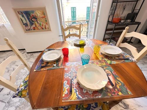 a wooden table with plates on it in a room at SANREMO Mare e Relax - Affittasi Alloggio della Piazza con Aria condizionata, Balcone e ampia disponibilità di parcheggi liberi in Sanremo