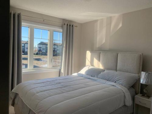 a white bedroom with a bed and a window at Brand new house in Ottawa