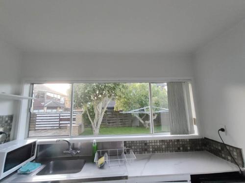 fregadero de cocina y ventana con vistas a un patio en Small 2-bedroom flat at Rangiatea Road, Epsom, Auckland, en Auckland