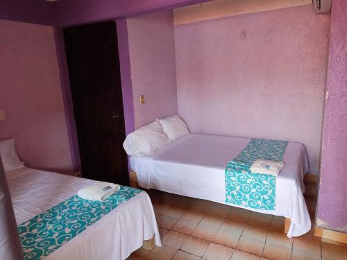 two twin beds in a room with purple walls at Hotel Casa Lucina in Zihuatanejo