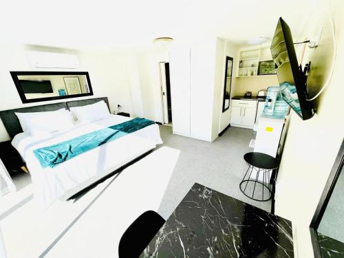 a white bedroom with a bed and a kitchen at Hotel Vibes Cape Town Plattekloof in Cape Town