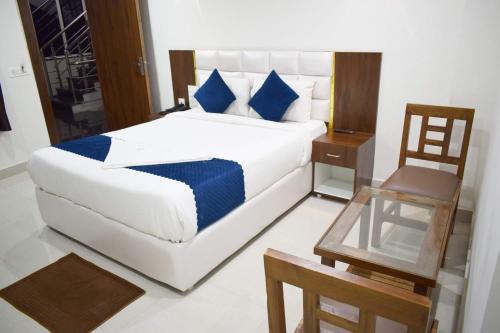 a bedroom with a large white bed with blue pillows at Hotel SkyLand in Warangal