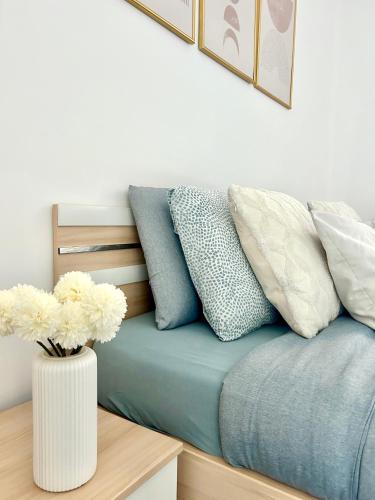 a bed with pillows and a vase with flowers on it at The Lakeside Apartment - Strategic position! in Lugano