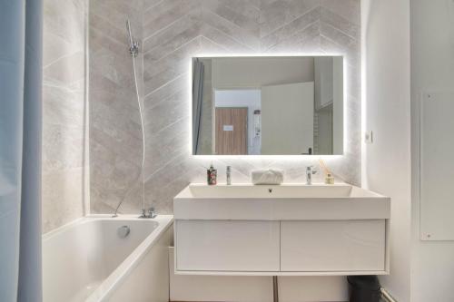 une salle de bain blanche avec un lavabo et un miroir dans l'établissement Appartement I Confort et Lumineux I 2 min du métro, à Toulouse