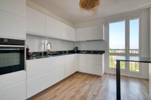 une cuisine avec des placards blancs et une grande fenêtre dans l'établissement Appartement I Confort et Lumineux I 2 min du métro, à Toulouse