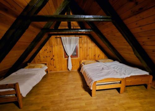 deux lits dans une chambre mansardée avec une fenêtre dans l'établissement Mi-Ma Land, à Donje Orešje