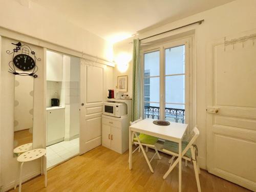 une petite cuisine blanche avec une table et une fenêtre dans l'établissement Paris Center Quarter Latin Nice 1 bedroom, à Paris