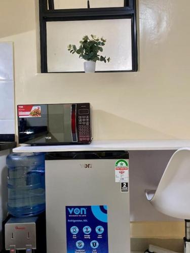 a microwave and a plant on top of a refrigerator at Delight Studio, Kaisa Gardens Kileleshwa in Nairobi