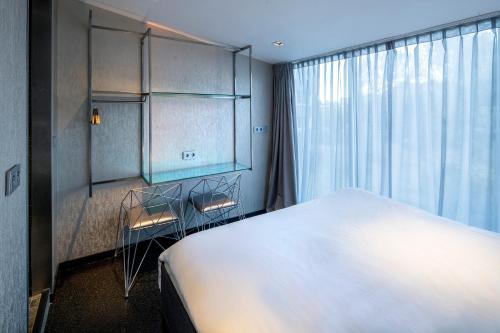 阿姆斯特尔芬Diamond Capsule Hotel Amsterdam South的卧室里有一张白色的大床和一扇窗户