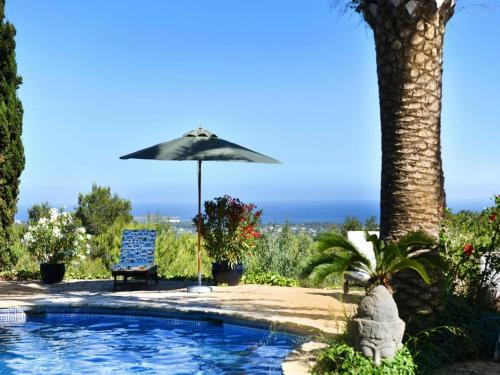 an umbrella and a chair next to a swimming pool at Apartment in Ibiza near Cala Conta Beach in Sant Carles de Peralta