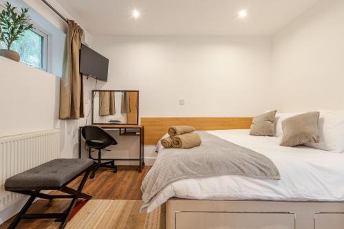 a bedroom with a bed and a desk and a chair at Parkside Haven, Modern 2-Bed Flat with Ensuites, Free Parking & Self Check-In in Perivale