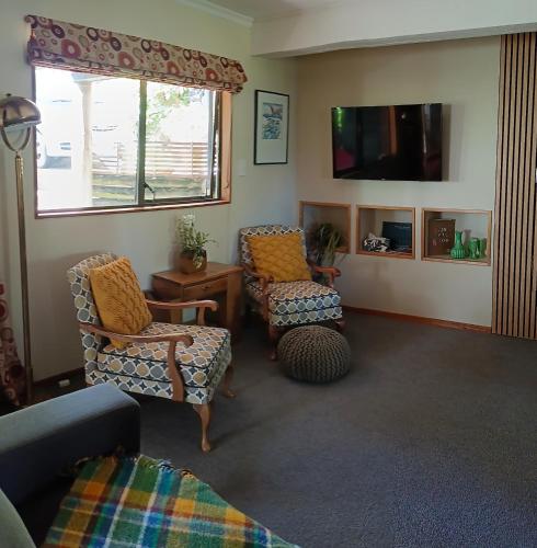 a living room with two chairs and a tv at Tahunanui holiday apartment in Nelson