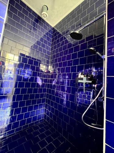 a blue tiled bathroom with a shower and a sink at Scheepmakershaven in Schoonhoven