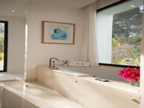 a white bathroom with a tub and a window at Villa in Ibiza near Salinas Beach in Sant Llorenç de Balafia