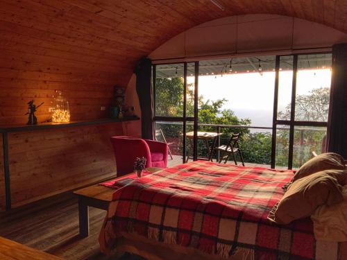 a bedroom with a bed and a large window at Finca El Tambor Nature Reserve, Lodging and Tours in Antigua Guatemala