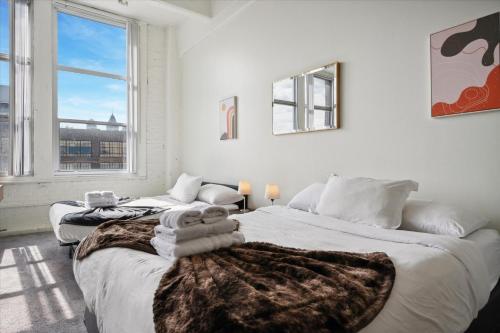 two beds in a white room with a large window at Loft640 Studio, Free Parking, Kitchen, Workspace, Great Location in Philadelphia