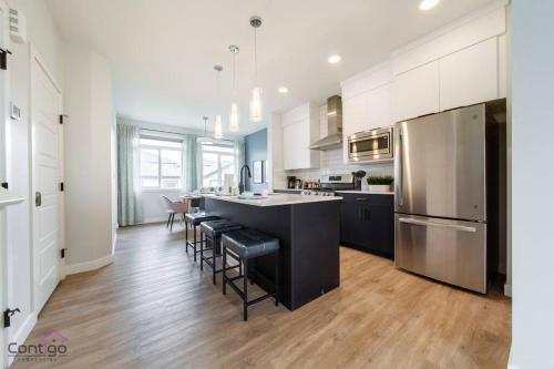 a kitchen with a large black island with bar stools at The Nest, 3BR, AC, Near YEG Airport, King Bed! in Edmonton