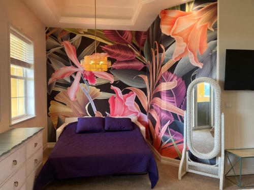 a bedroom with a purple bed and a flower mural at the Cape House in Cape Canaveral