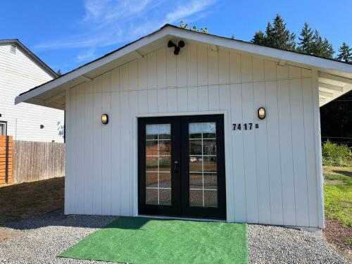 a white building with a door and a green floor at Modern Studio in MarysVille A Forest Haven in Marysville