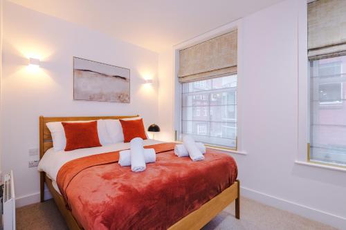 a bedroom with a large bed with orange and white pillows at Stylish 3-Bed Central Stay - Roof Terrace & Parking in Manchester