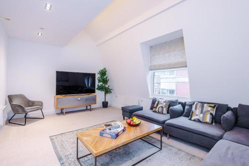 a living room with a couch and a table at Stylish 3-Bed Central Stay - Roof Terrace & Parking in Manchester