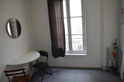 Cette chambre blanche dispose d'une table et d'une fenêtre. dans l'établissement Studio Paris 18, à Paris