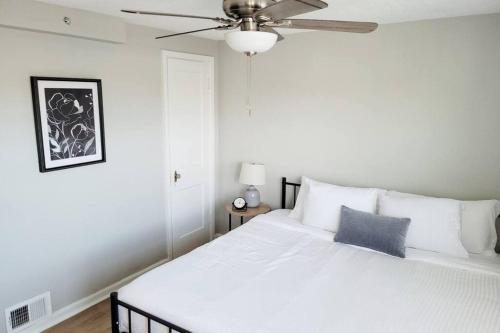 a bedroom with a white bed with a ceiling fan at Davenport Dwellings-Walk to UNMC in Omaha