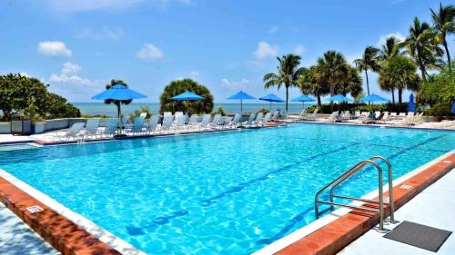 a large swimming pool with chairs and umbrellas at Conch in the Treetops by Last Key Realty in Key West