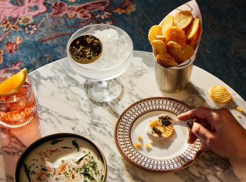 a table with a plate of food and a bowl of chips at The Manner, The Unbound Collection by Hyatt in New York