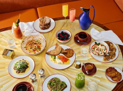 a wooden table with plates of food on it at The Manner, The Unbound Collection by Hyatt in New York