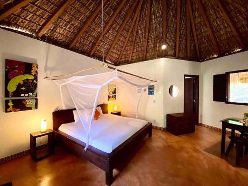 a bedroom with a bed with a mosquito net at Cabaña El Cactus Playa Mermejita in Mazunte