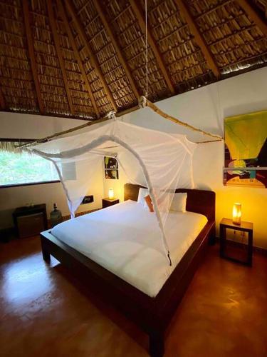 a bedroom with a bed with a mosquito net at Cabaña El Cactus Playa Mermejita in Mazunte