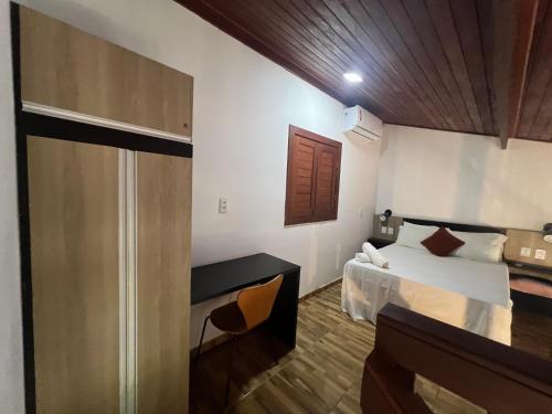 a bedroom with a bed and a desk in a room at Pipa Golfinhos Pousada in Pipa
