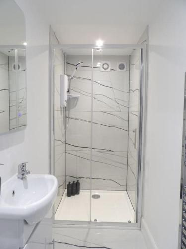 a white bathroom with a shower and a sink at Modern 3BHK near Edinburgh zoo in Edinburgh